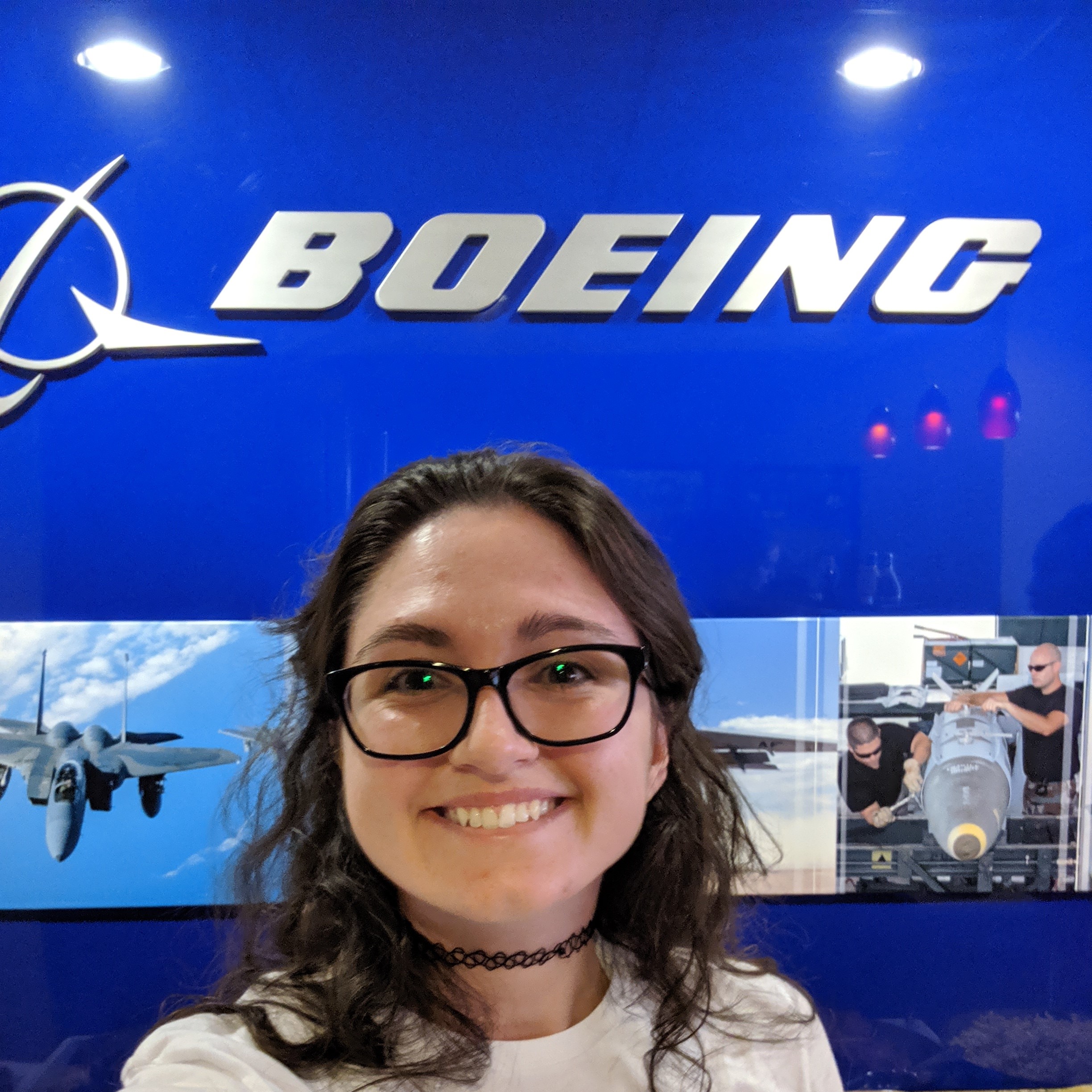 Kaitlyn smiling in front of Boeing blue wall and logo.